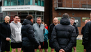 Thumbnail: Group of people stood outside AXA Melwood Training Centre next to the sign with coach behind